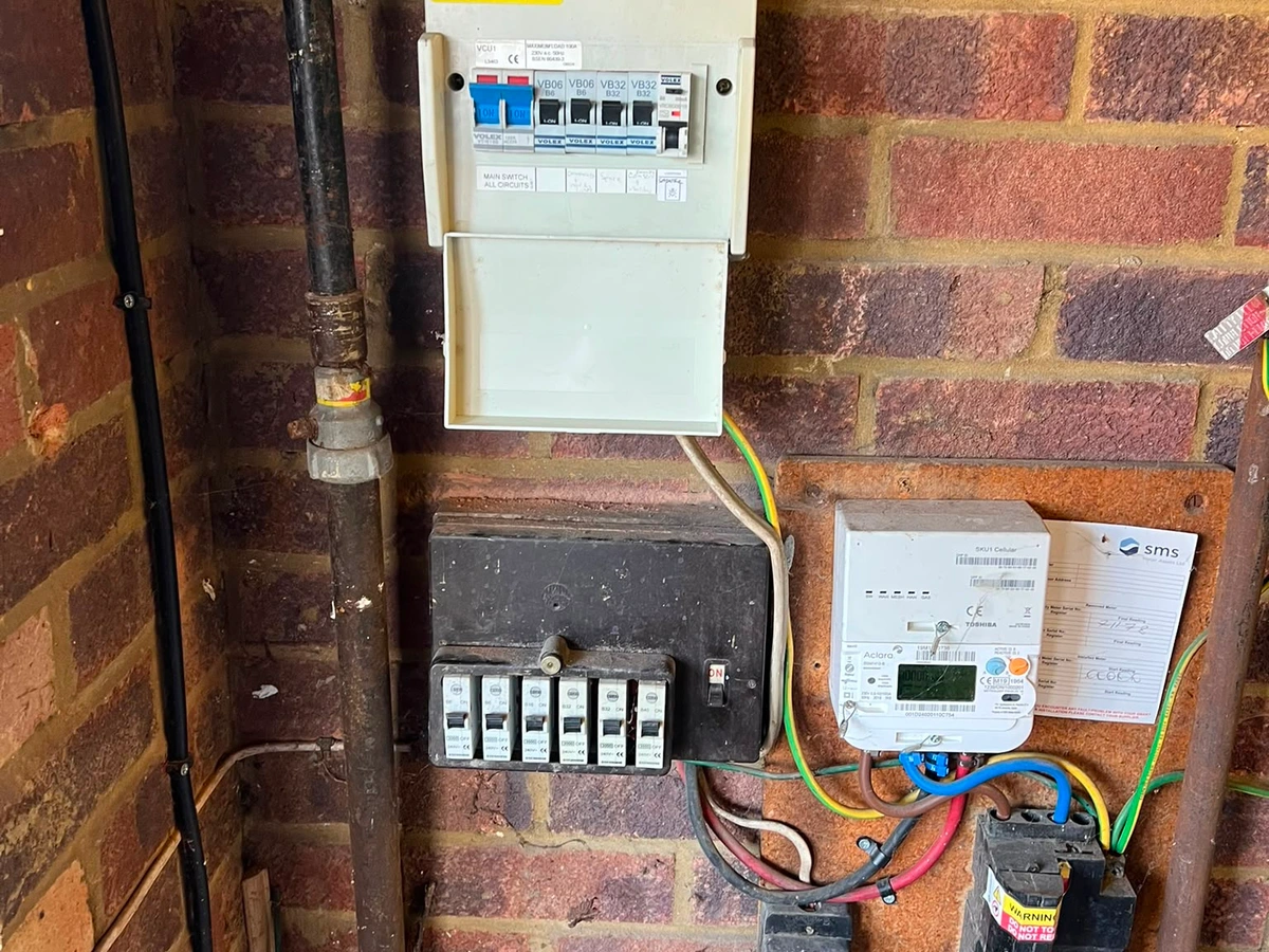 Small consumer unit fitted above the meter on a brick wall